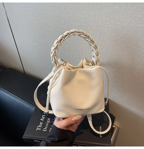 Detail of white lychee pattern leather bucket bag with woven handle and drawstring closure