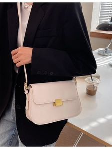 Vintage cream square shoulder bag with gold clasp shown on a person in a modern blazer