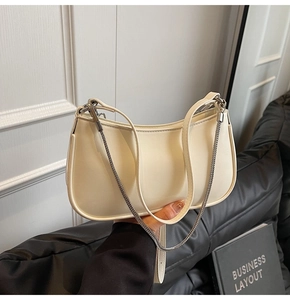 Detail shot of a cream crescent shoulder bag with silver chain and leather strap