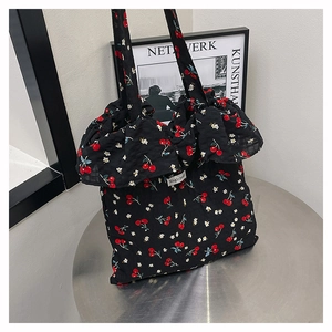 Detail of canvas tote bag featuring cherry print, ruffle trim, and a white logo patch