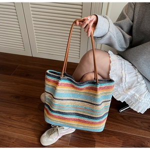 Detail of colorful striped woven tote bag with brown leather straps and textured fiber