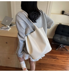 Detail showing white bucket bag with crocodile pattern texture and wide shoulder strap