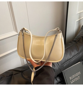 Detail of creamy yellow crescent shoulder bag with slim leather strap and silver chain