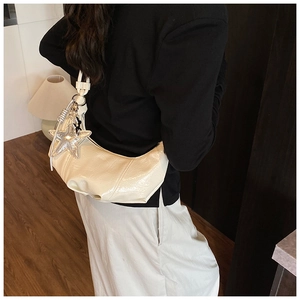 Détail d'un sac demi-lune blanc crème en cuir verni plissé avec breloque étoile argentée