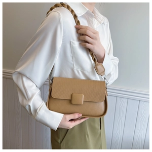 Detail view of khaki textured crossbody bag with thick woven strap and silver buckle
