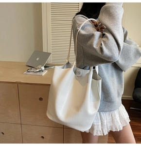 Detail of white crocodile embossed tote bag showing the magnetic buckle and texture