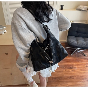 Detail of black large tote bag with butterfly pendant and pearl tassels on model