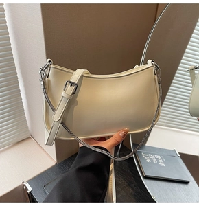 Detail of white half-moon hobo bag with adjustable leather strap and silver metal chain