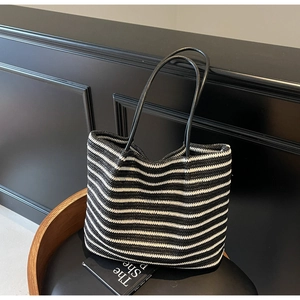 Detail shot of black and white striped woven tote bag with slim leather straps on chair