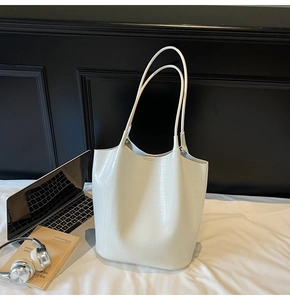Close-up of white crocodile pattern tote bag with laptop and office essentials