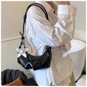 Détail du sac croissant plissé noir avec pendentif étoile argentée sur chemise blanche