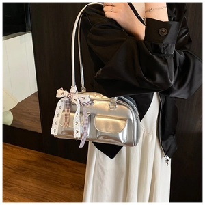 Detail of silver metallic shoulder bag with two front pockets and lace bow decoration