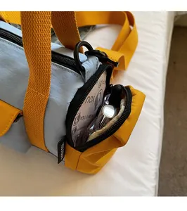 Detail view of the contrast color barrel bag side pocket with light blue and yellow nylon fabric