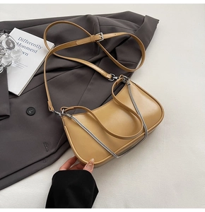 Detail of tan faux leather baguette bag with silver chain and adjustable shoulder strap