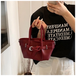 Détail du sac seau en cuir bordeaux avec boucle argentée et attaches latérales en D
