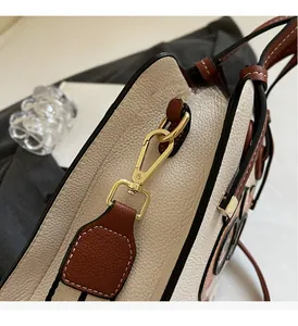 Close-up of golden hardware and cartoon eye detail on leather tote bag strap
