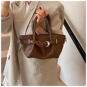 Détail du sac seau en cuir marron foncé avec anneau métallique argenté et ceinture décorative