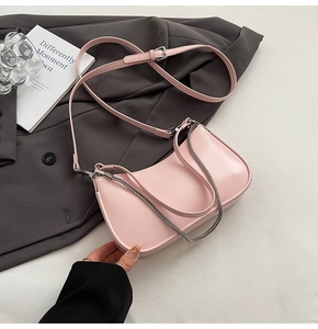 Pink crescent moon bag with adjustable strap and silver chain detail on grey suit