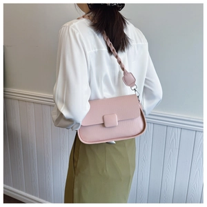 Detailed view of pale pink crossbody bag with unique woven shoulder strap on a model