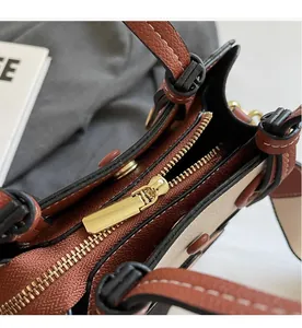 Detailed macro view of the smooth golden zipper and lychee textured faux leather on tote bag