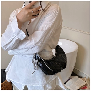Détail du sac bandoulière en croissant noir avec texture plissée et breloque papillon