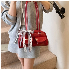 Detail of red patent leather pillow bag with twin pockets and decorative ribbon bow