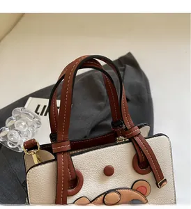 Close-up of contrast leather tote bag with stitch bear detail and gold hardware