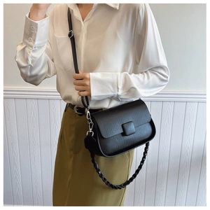 Detail of black pebbled leather crossbody bag with decorative chain and square buckle