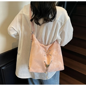Detail of pink tie-dye hobo bag featuring metal chains and a butterfly pendant
