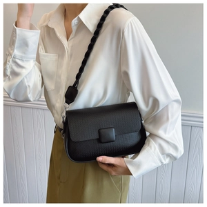 Detail of black crossbody bag featuring fine woven texture and braided shoulder strap