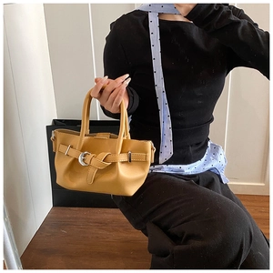 Détail du sac à main en cuir jaune vif avec boucle de ceinture décorative et poignées rondes