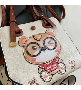 Close-up of beige lychee grain tote with a cute cartoon bear and brown leather handles