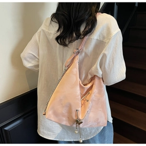 Light pink satin tote bag with pearl butterfly charm and chain details shown on model
