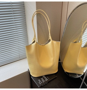 Detail of bright yellow tote bag with crocodile pattern and long shoulder straps