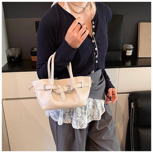 Sac seau chic blanc crème avec boucle décorative porté par un mannequin