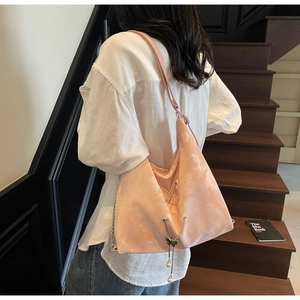 Detail of salmon pink tote bag featuring metallic accents and butterfly pearl charms