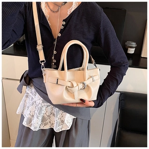 Détail d'un sac seau crème montrant la boucle décorative et la bandoulière amovible