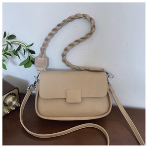 Detail of beige shoulder bag featuring woven handle and textured faux leather finish