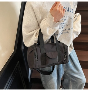 Detail of a black nylon Boston bag showing the cylindrical shape and detachable strap