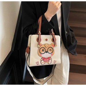 Detailed view of cream tote bag featuring a cute cartoon bear and wide fabric strap