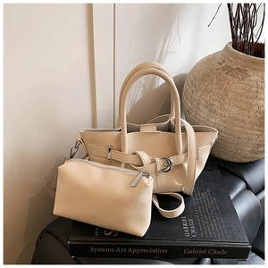 Détail du sac seau beige avec pochette assortie et boucle sur surface noire