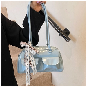 Detail of light blue glossy shoulder bag with dual front pockets and plaid ribbon bow