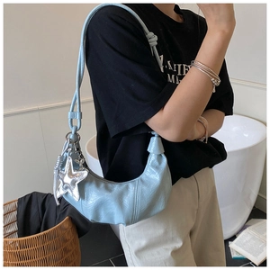 Detail view of light blue pleated croissant bag with silver starfish charm and knotted strap