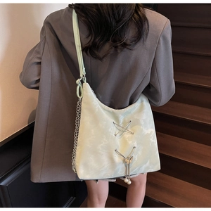 Detail of mint green tote bag with metal chain and pearl butterfly pendant on stairs