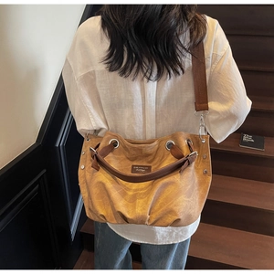 Close-up of khaki canvas tote bag showing thick brown straps and metal eyelet details