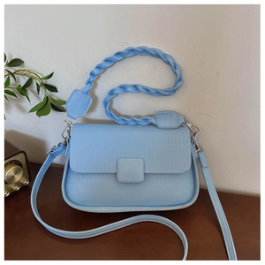 Detail of light blue crossbody bag with woven handle and square buckle on wooden surface