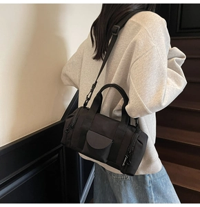 Close-up of black Boston bag featuring text-printed webbing and minimalist design detail