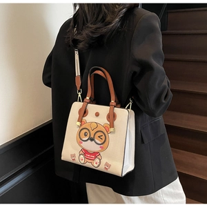 Close-up of a cream tote bag with cartoon bear print and stylish brown leather straps