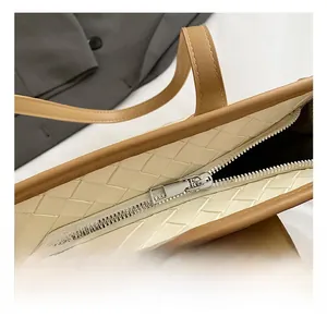 Close-up of the woven tote bag showing the silver metal zipper and dual-tone texture