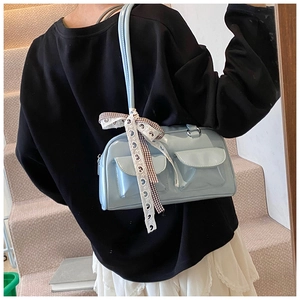 Detail of light blue shoulder bag with front flap pockets and plaid bow accent
